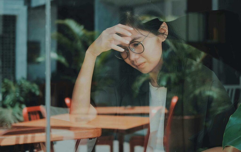 Frau stützt sich unzufrieden auf einen Tisch ab und wirkt nachdenklich.