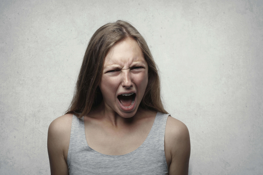 Frau ist ausser sich vor Wut nach einer Trennung und verzerrt wütend ihr Gesicht bei einem Schrei