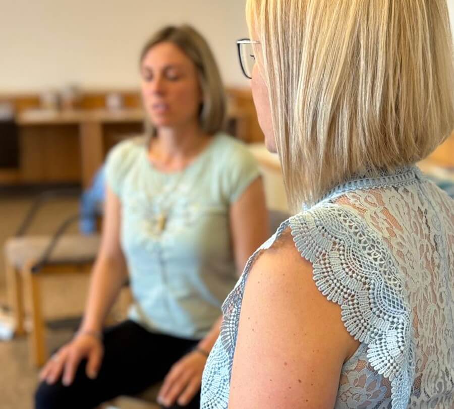 Zwei Frauen atmen die 4-7-8- Atemübung. Tägliche Atemübungen können dich positiv bei der Stressregulation unterstützen.